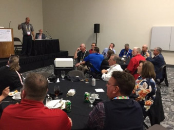 MikeGeorge (standing) and Roy Nance addressed a packed room of in-plant managers.