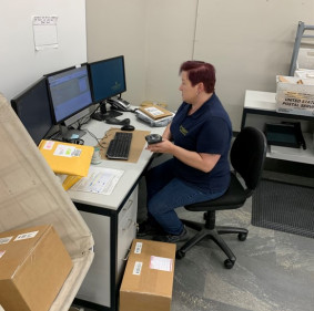 Paula Sluder processes incoming packages using Brynka tracking software, which updates the delivery status directly to the USPS website.