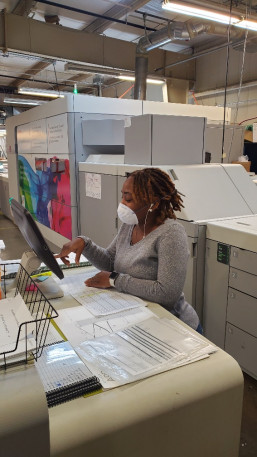 At Houston Independent School District Printing Services, Darian Craver runs the Canon VarioPrint i300 inkjet press, wearing typical in-plant facial attire in the age of COVID-19. 
